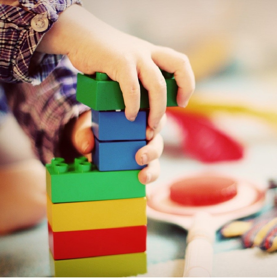un bambino impila dei cubetti di lego